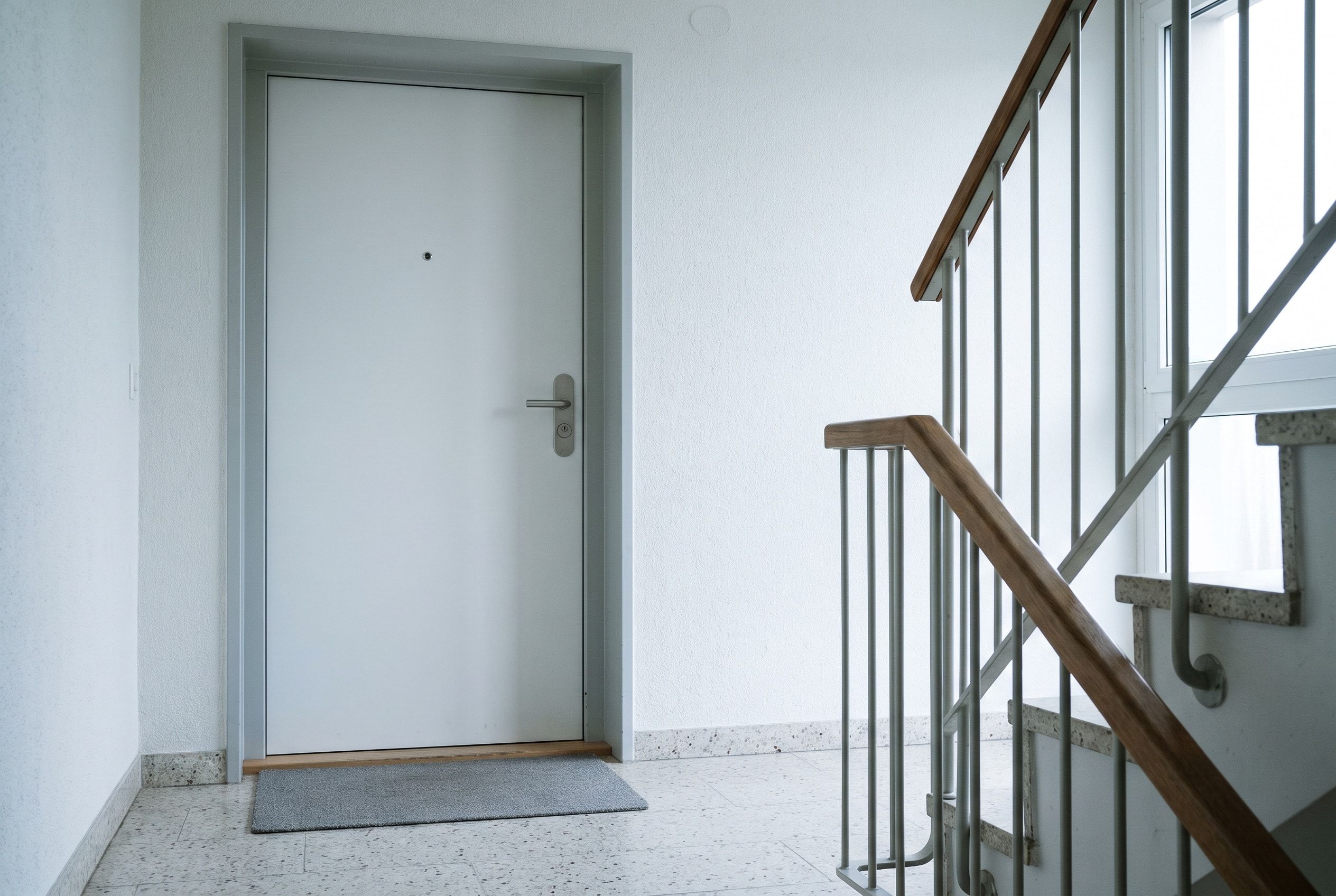 Geschlossene weisse Wohnungstür im Treppenhaus eines Mehrfamilienhauses